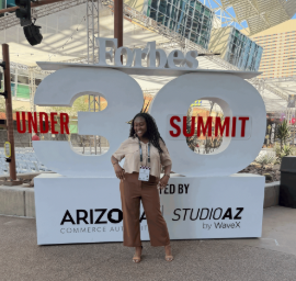 Tobi Ojo standing in front of the Forbes 30 Under 30 sign